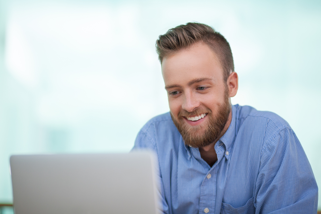 Cheerful bearded Caucasian man using laptop or businessman working in office